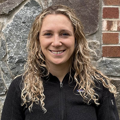 Dr. Duggan poses for a photo in front of a stone wall